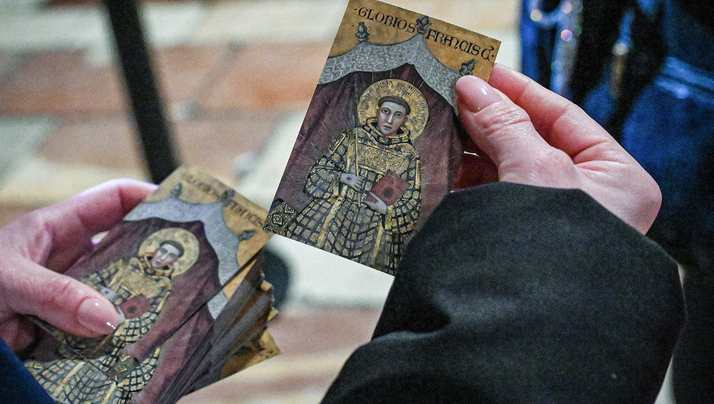 Eine Person hält Heiligenbilder des heiligen Franziskus von Assisi