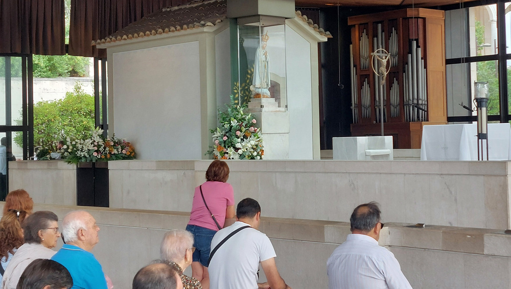 Menschen beten vor Marienstatue im Wallfahrtsort Fatima